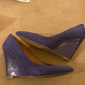 A pair of purple suede wedge pumps.